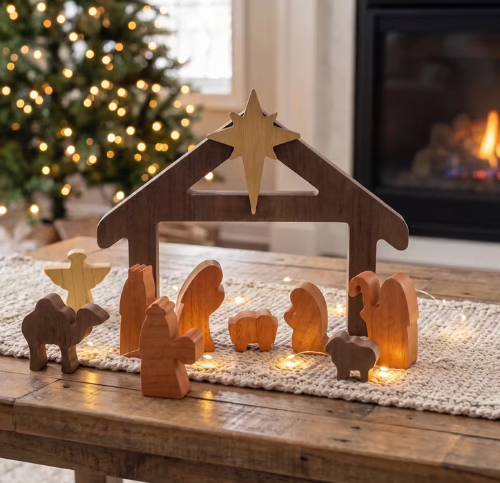 Minimalist wooden Nativity set displayed on a rustic table beside a Christmas tree and fireplace, with decorative lights