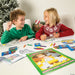 Two children colouring Nativity story activity pages at a Christmas table with the A King Is Born colouring book