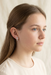Teenage girl with long brown hair and blue eyes wearing the silver cross stud earrings in a three-quarter profile portrait